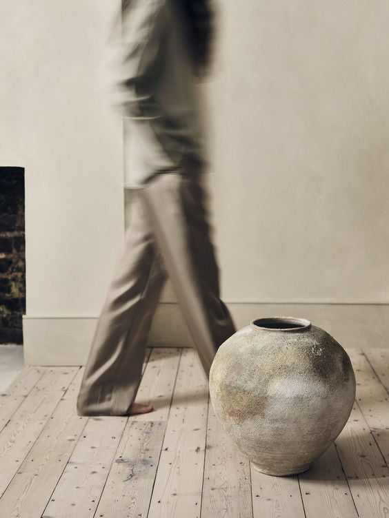 woman walking past clay pot inside Brand Rich IRL concept.